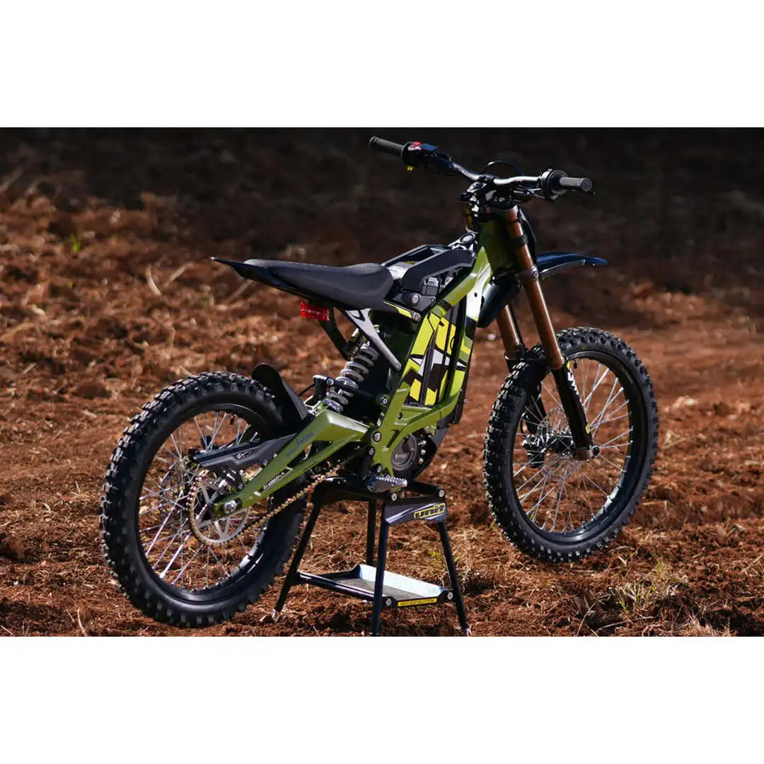 A green and black Husqvarna dirt bike standing on a kickstand on a dirt track.