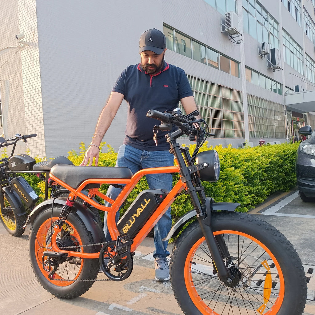 Man interacting with an orange electric bike in an urban setting