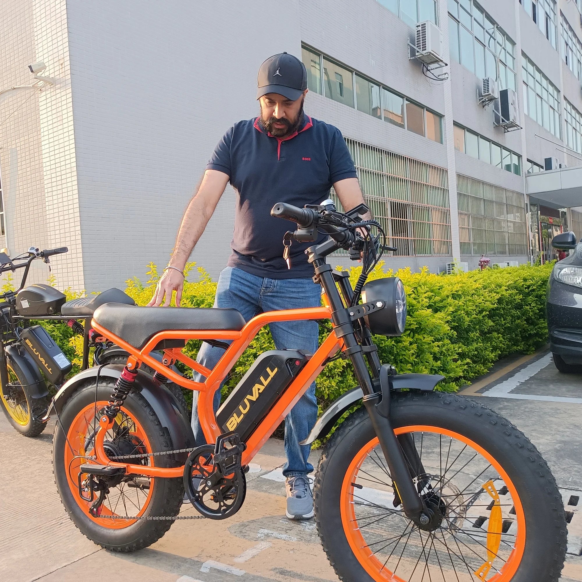 Man interacting with an orange electric bike in an urban setting