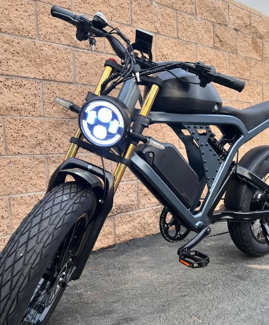 Electric bike with a unique headlight design against a brick wall.