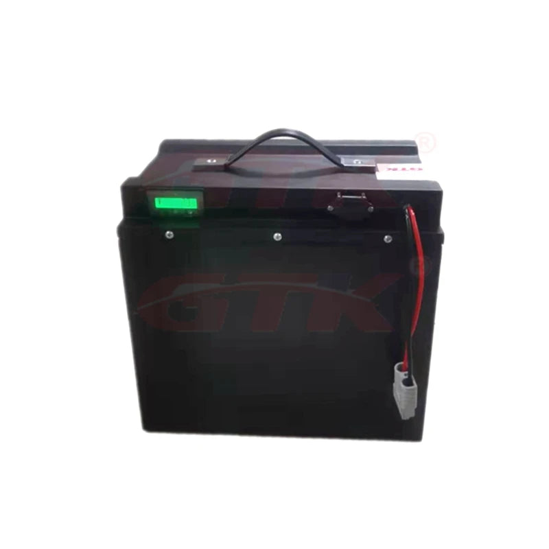 A black rectangular battery with a top handle, a small green display window, and a red wire with a connector on the right side, shown against a plain white background.