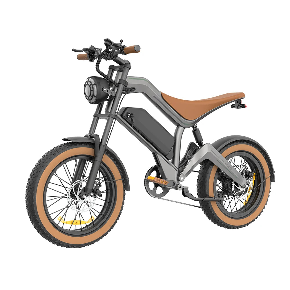 A modern electric fat-tire bike with a matte gray frame, brown leather saddle, and tan sidewall tires, shown from a three-quarters front angle on a white background.