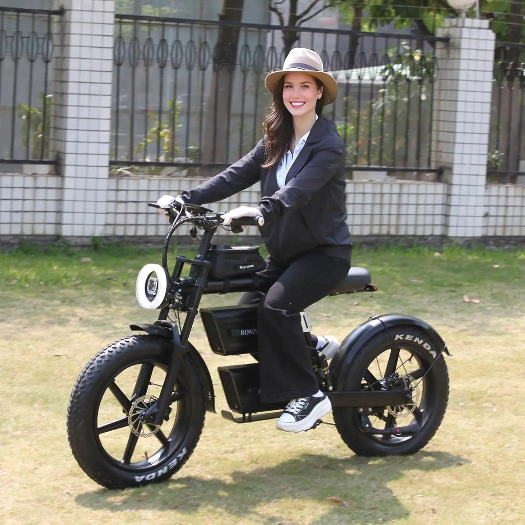 Woman riding a black electric bike outdoors on a sunny day.