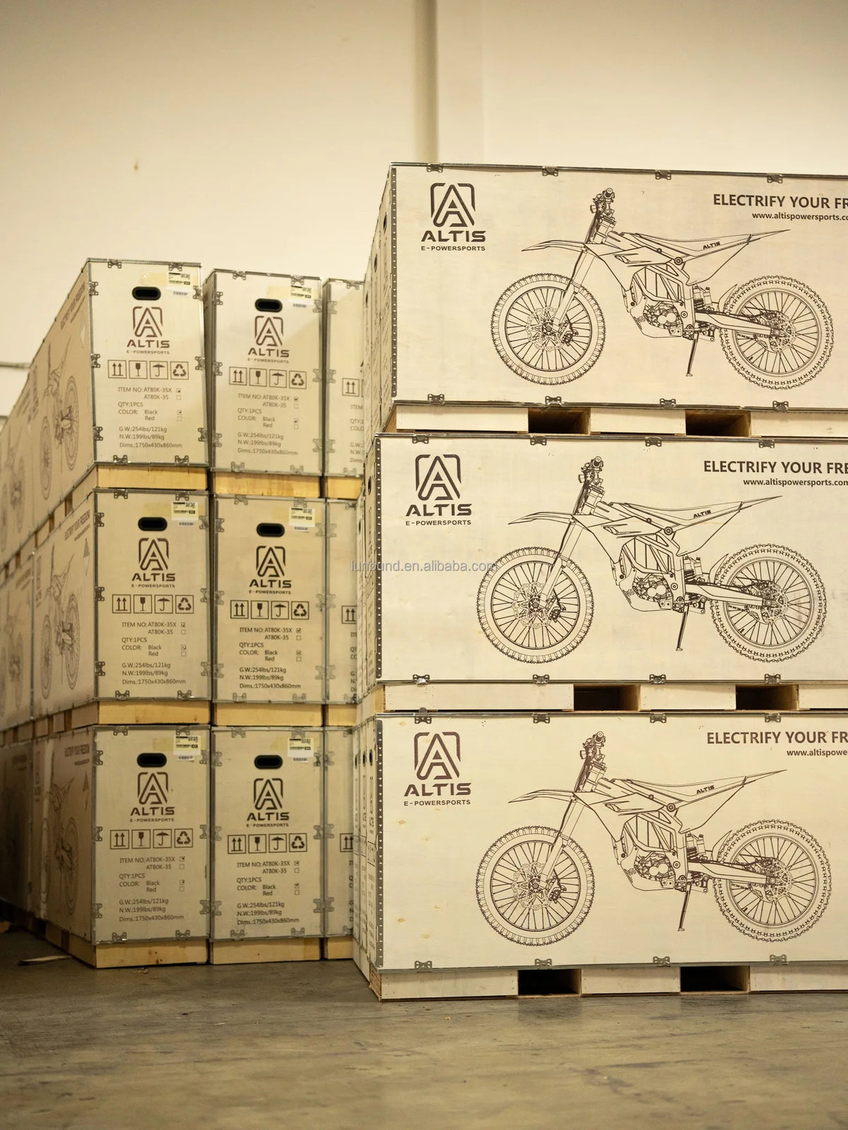 Stack of cardboard boxes with Altis electric bike illustrations on a wooden floor.