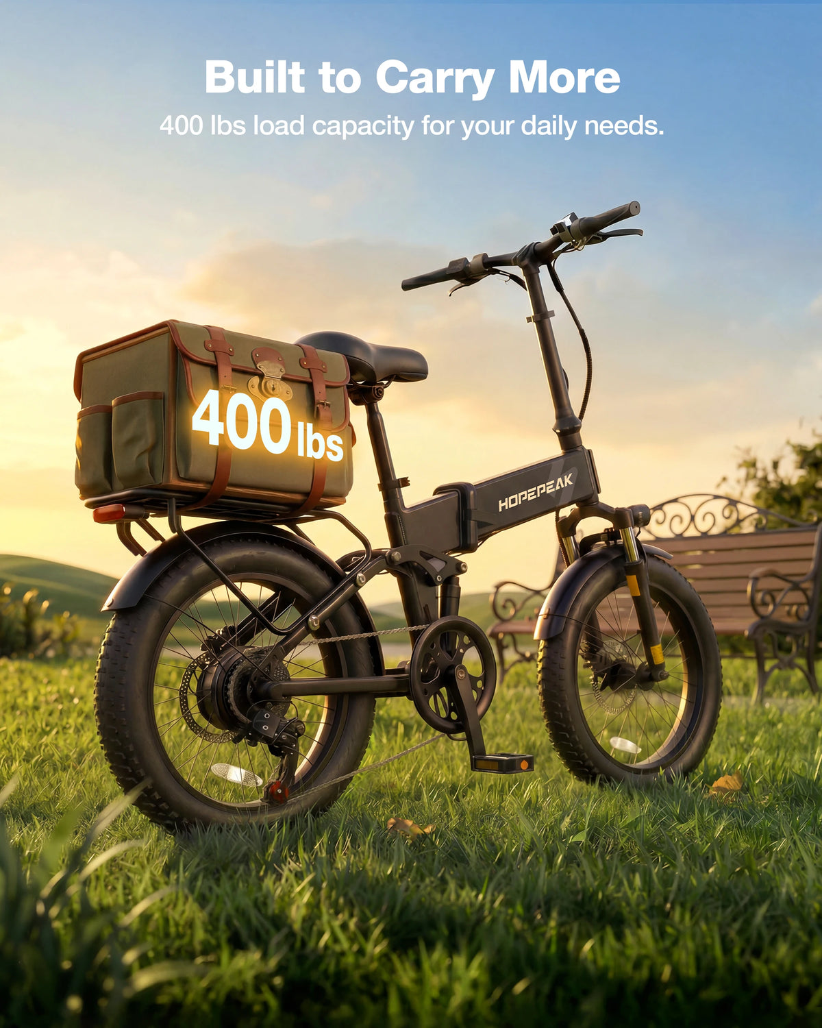 A black electric cargo bike with a large brown and green utility box on the rear rack, parked on a grassy field at sunset. The bike has a battery mounted on the frame, and the text 'Built to Carry More 400 lbs load capacity for your daily needs.