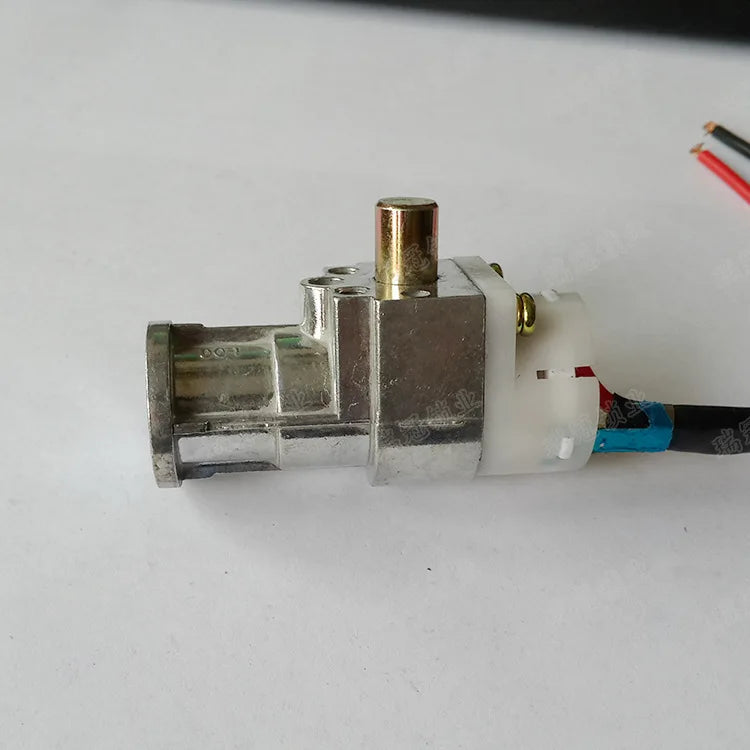 A small metal electrical component with a brass-colored cylindrical pin on top, a white plastic connector housing, and attached wires in blue, red, and black, photographed on a plain light background.