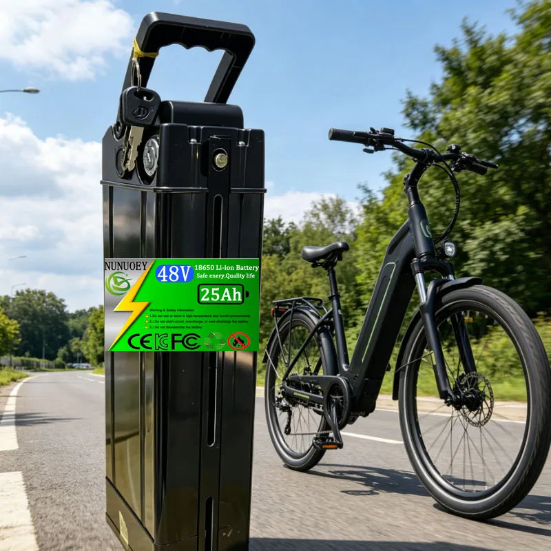 A black NUNIOBEY 18650 Li-ion battery pack with a green and white label stands next to a black electric bicycle on an outdoor road with trees and blue sky in the background.