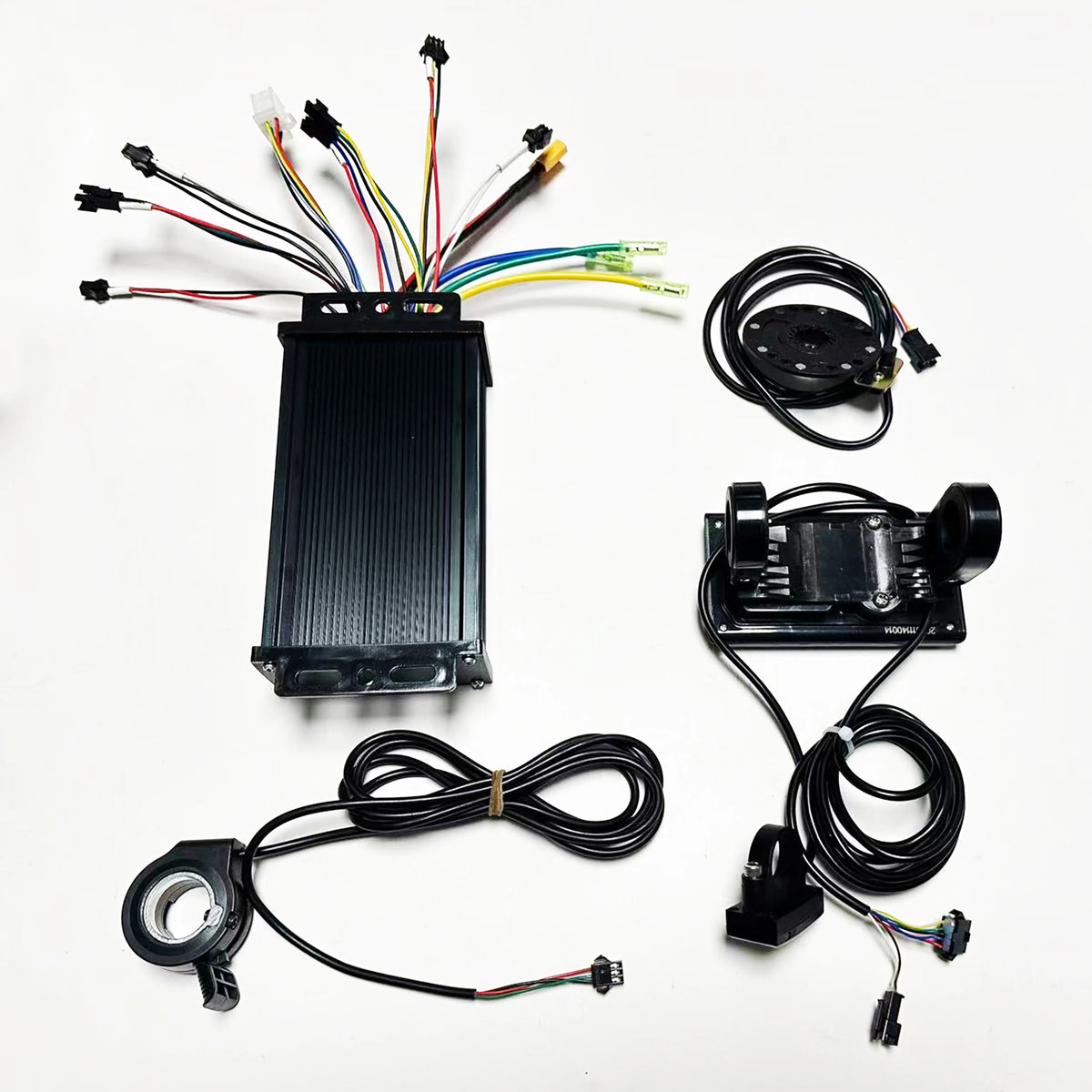 A black electronic control module kit with multiple attached and connected wires, shown laid out on a white background. The kit includes a central rectangular controller, a circular sensor or adapter, a rectangular sensor unit with attached cable, and a circular ring-shaped component with wire leads.