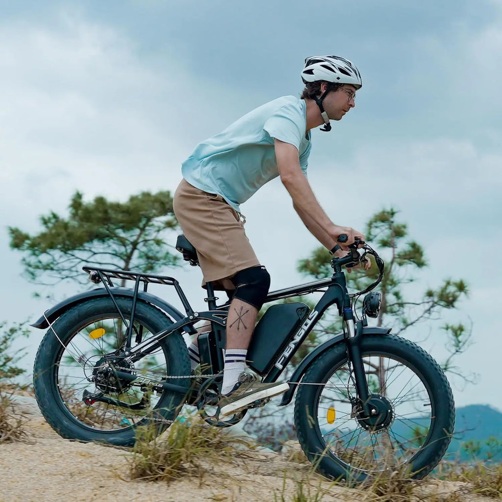 Person riding an electric bike on a trail with trees and mountains in the background
