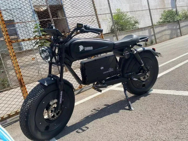 Black electric bike on a road with a fence and plants in the background