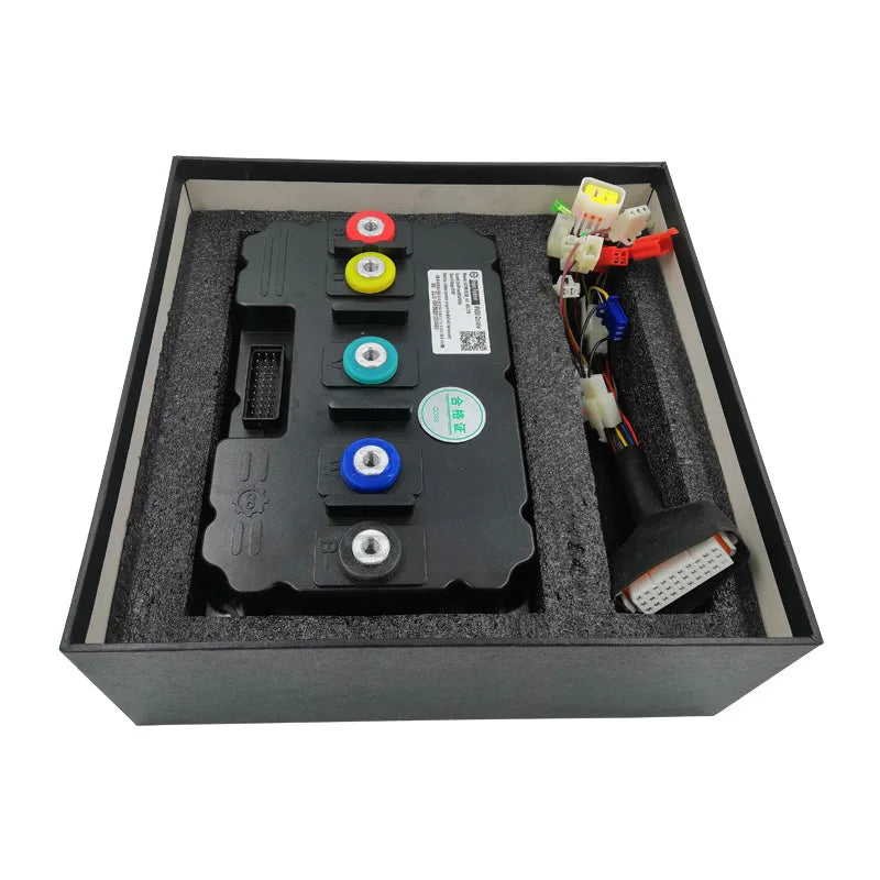 A black electronic control module with four colored terminal buttons (red, yellow, green, blue) and attached wiring harnesses, presented inside a black foam-lined gift box.