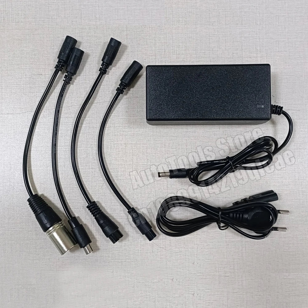 Black multi-connector power adapter kit with four flexible cords, one barrel connector, and one wall plug, laid out on a light beige textured background.