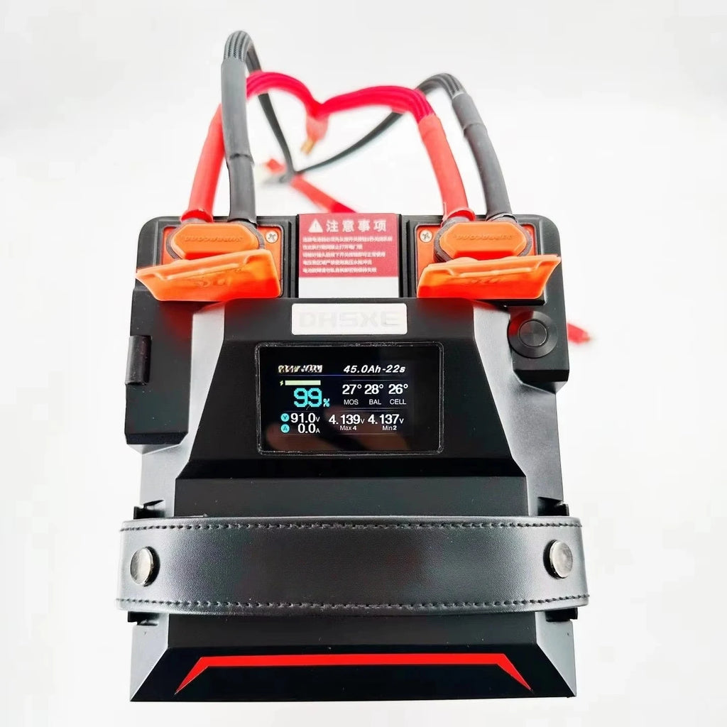 A portable jump starter battery with a digital LCD display screen, orange and red clamps, and a black leather strap around the middle, shown on a white background.