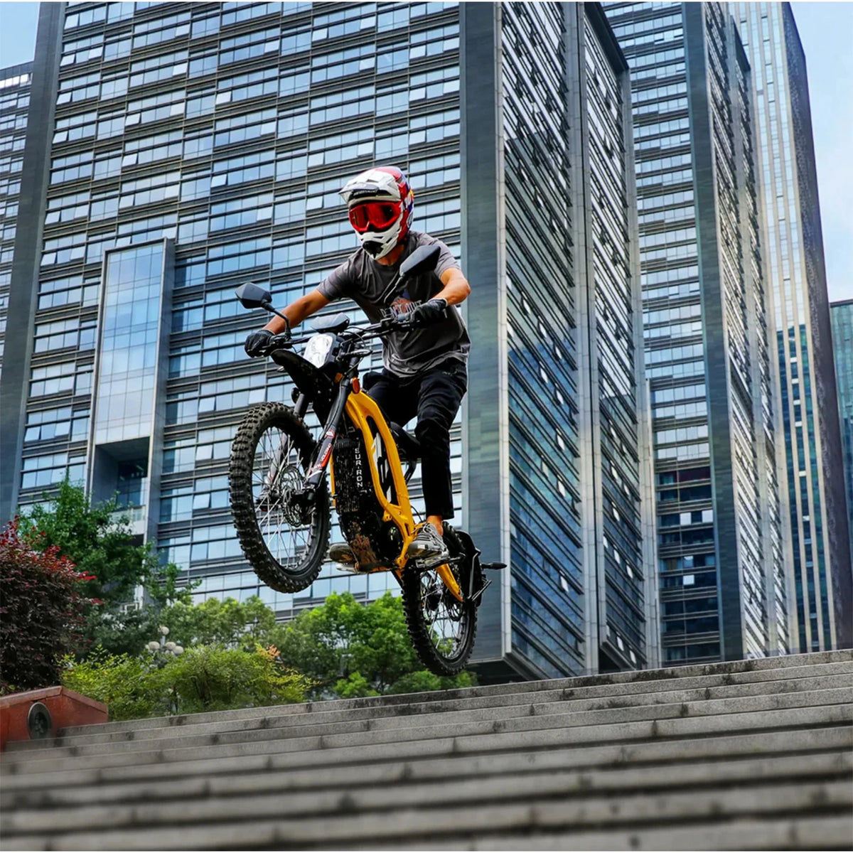 Person on a bicycle performing a trick in front of tall buildings